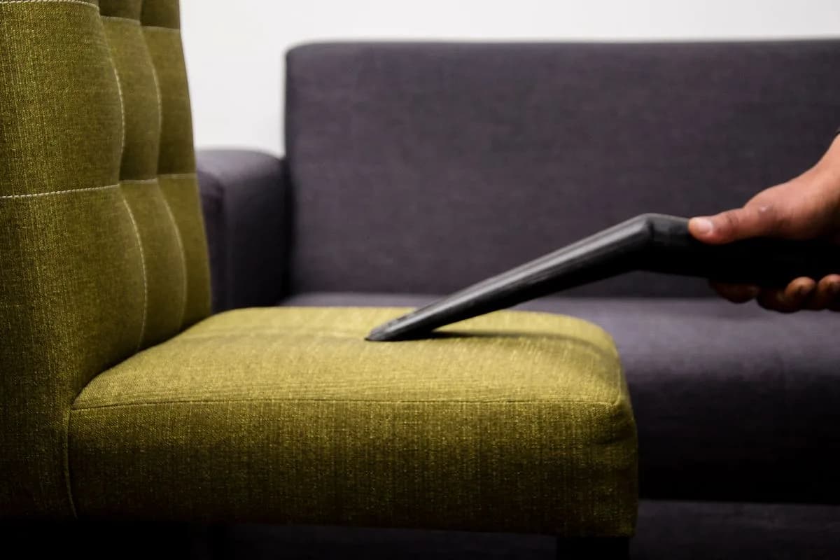 Vacuuming a fabric sofa during upholstery cleaning
