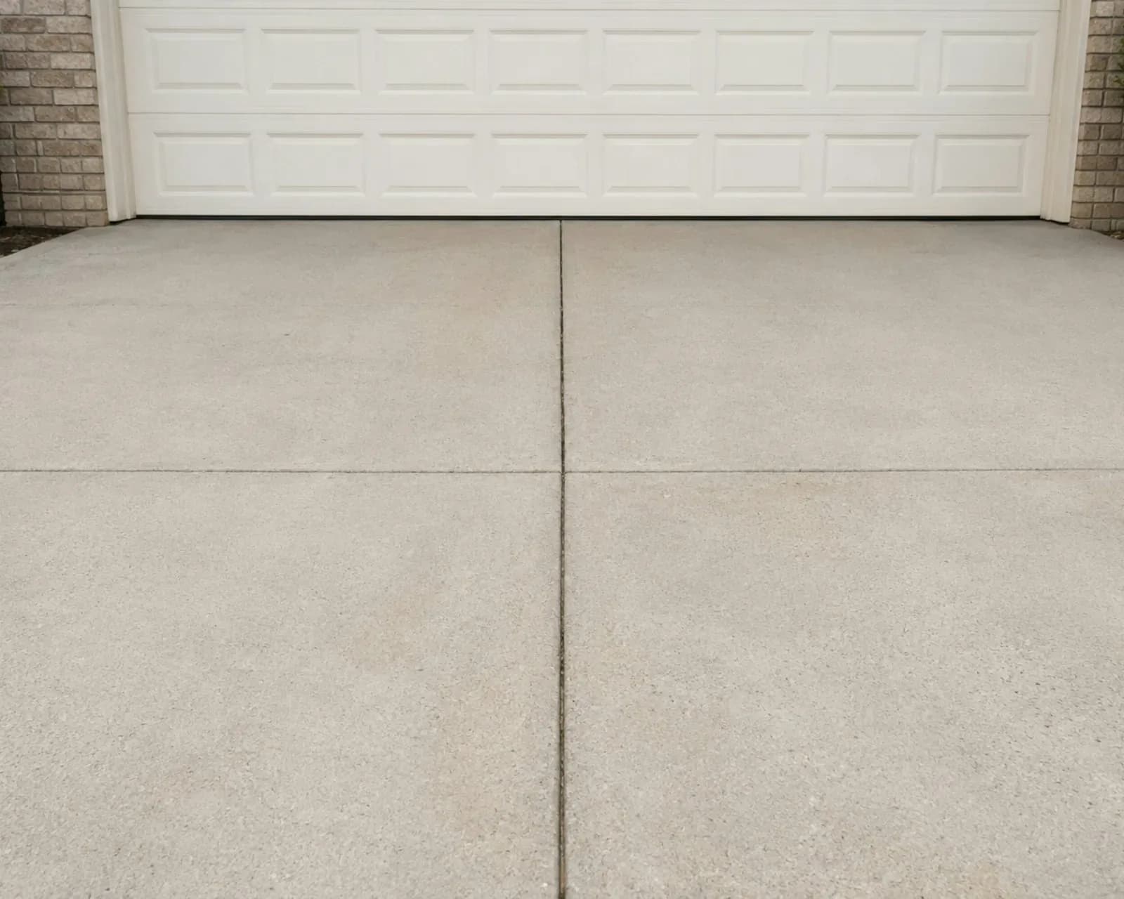 Clean concrete driveway in front of a white garage door
