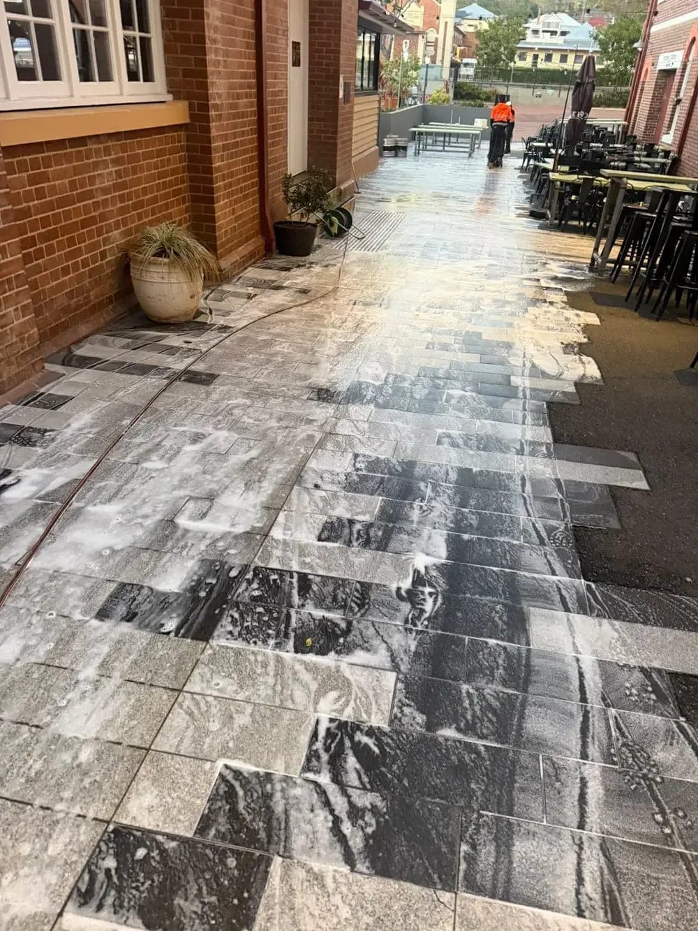 Pressure cleaning Brisbane: foam and high pressure wash on a paved commercial courtyard